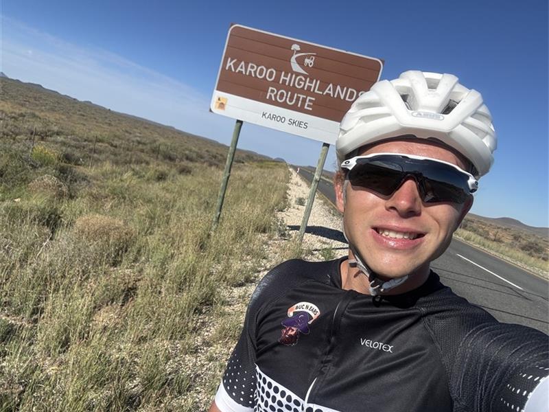 Cyclist standing in front of a brown road sign
