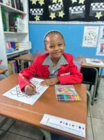 Black girl sitting at a desk colouring