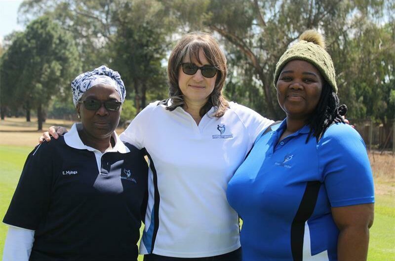 Three women standing on a gold course