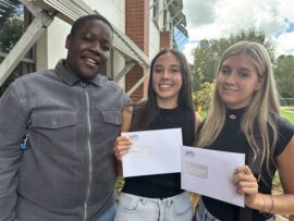 Three learners one boy and two girls holding envelopes