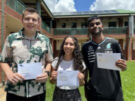 Three learners two boys and a girl holding envelopes