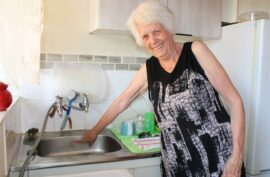 Elderly woman pointing to a kitchen sink