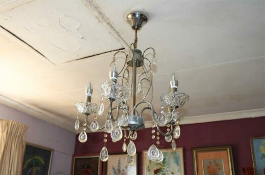 Crystal light fitting hanging from a stained ceiling