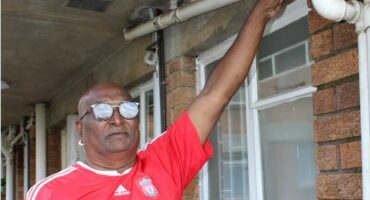 Indian man with red shirt pointing to a pipe