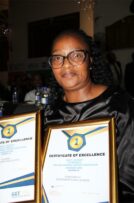 Black woman wearing glasses holding two certificates