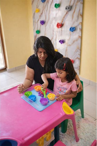 Indian woman sits next to an Indian girl at a pink table