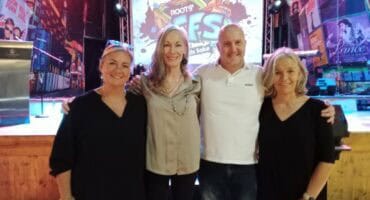 Four people, three women and a man in front of a screen