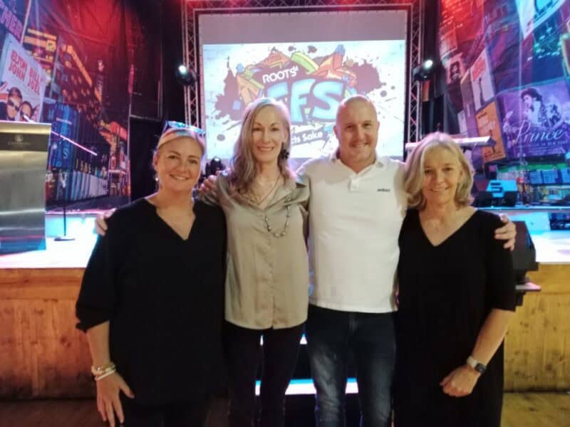 Four people, three women and a man in front of a screen