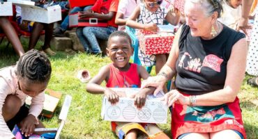 Woman sitting on her knees with a child unwrapping a gift