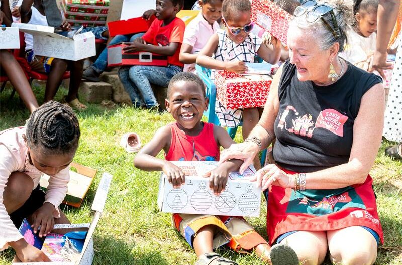 Woman sitting on her knees with a child unwrapping a gift