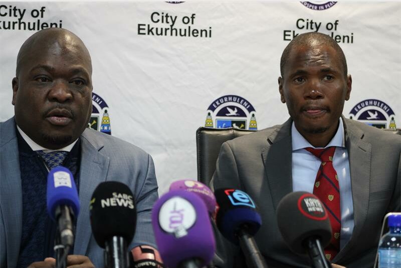 Two black men sitting in front of microphones