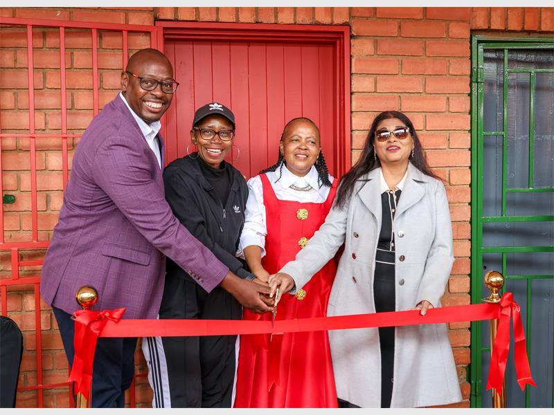 Four people about to cut a red ribbon