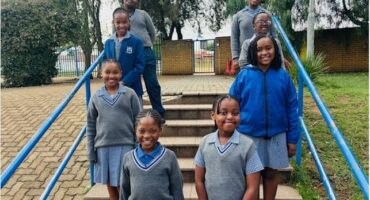Group of black children wearing blue uniforms standing on steps