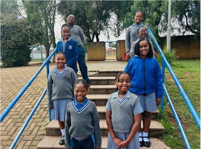 Group of black children wearing blue uniforms standing on steps