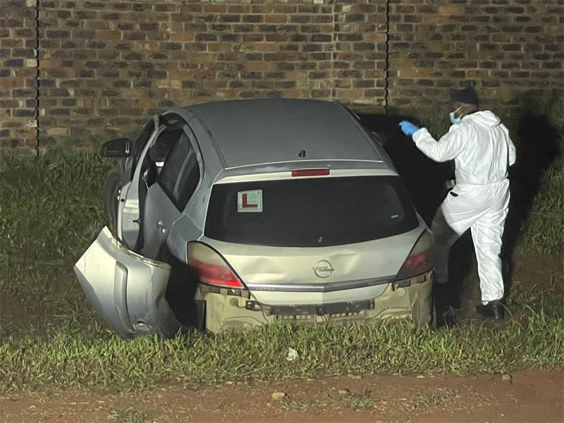 Man in white overall standing next to a car