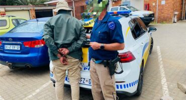 Police officer stands next to a man in handcuffs