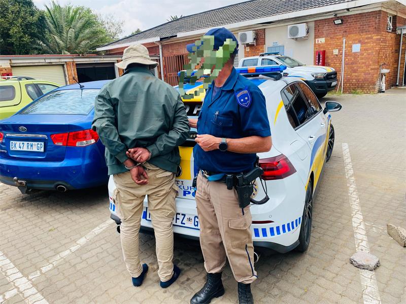 Police officer stands next to a man in handcuffs