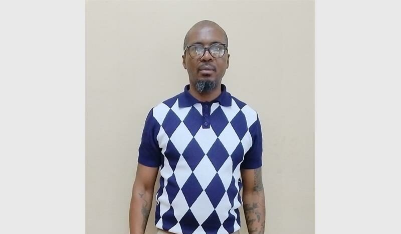 A man standing, wearing spectacles.