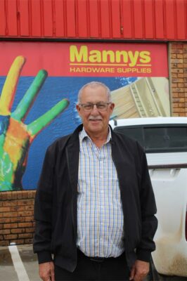 Elderly man with glasses standing in front of a business board