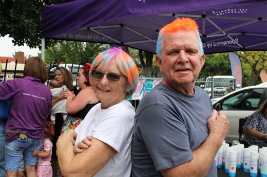Woman and man with brightly coloured hair stand back-to-back in a fun pose