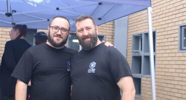 Two men standing next to each other smiling at the camera.