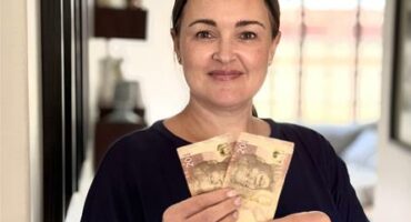 Woman wearing black holding two R20 notes