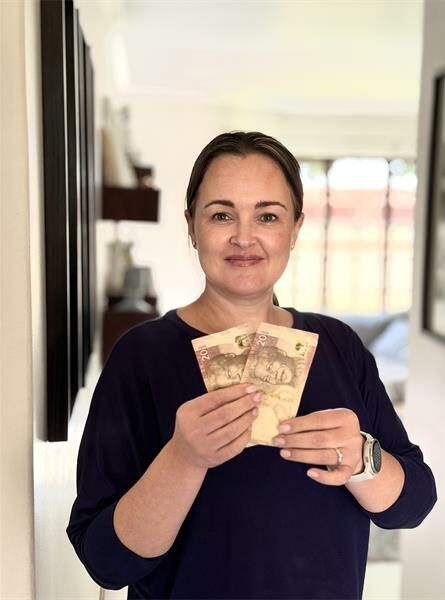 Woman wearing black holding two R20 notes