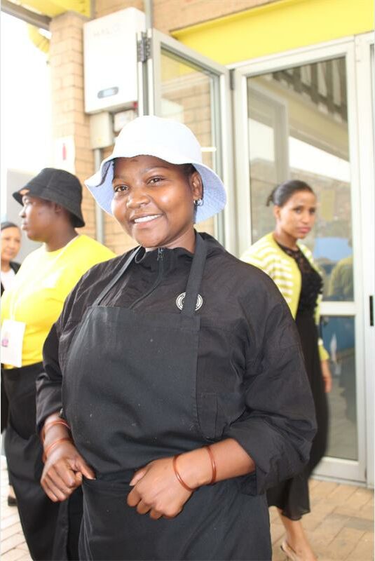 Black woman with white bucket hat and black chef's uniform