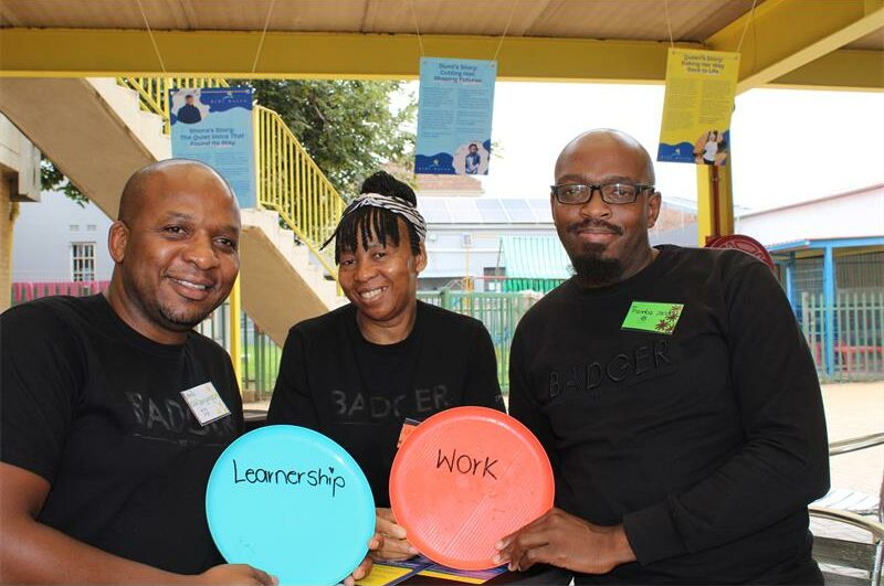 Two black men and women holding circular discs