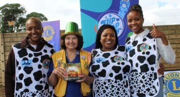 Four women, three wearing cow print bibs