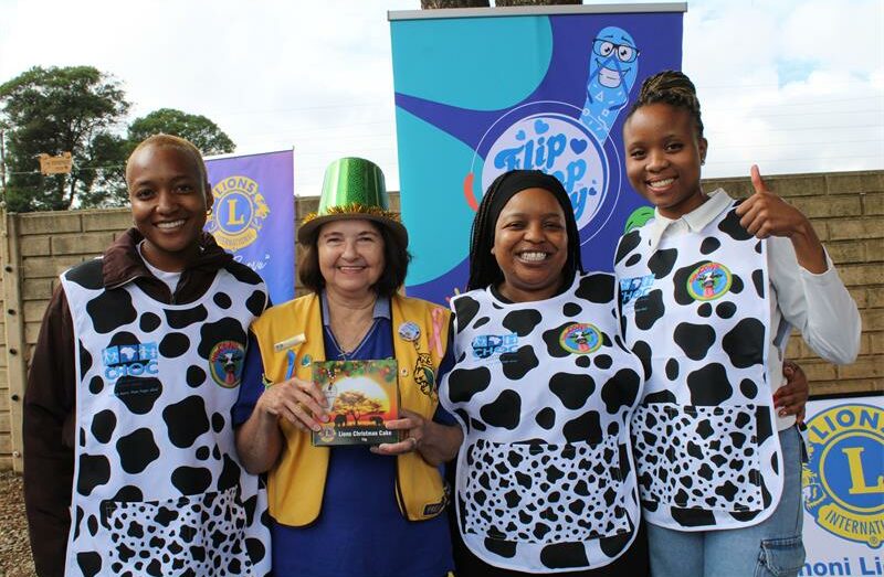 Four women, three wearing cow print bibs