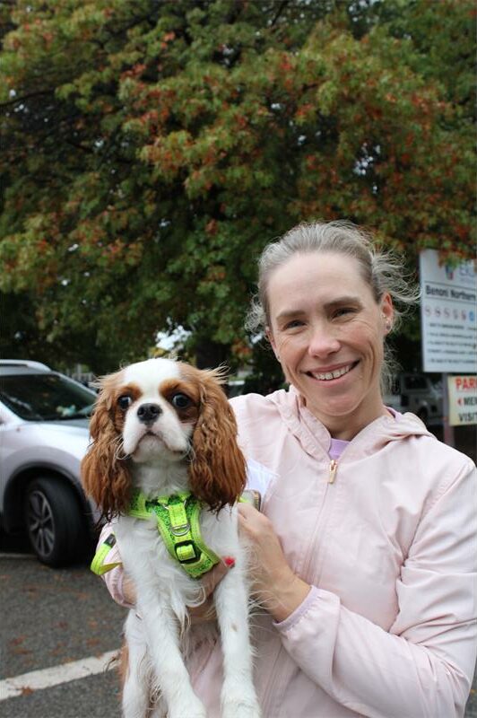 Woman wearing a pink jacket holding a dog