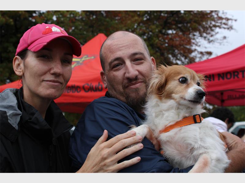 Woman with pink cap and bald man holding a dog