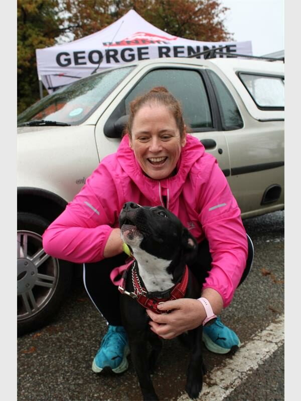 Woman in pink jacket laughs as dog howls
