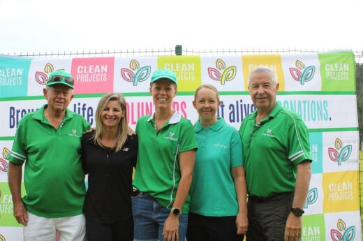 Four people, two men and three women standing in front of a banner.