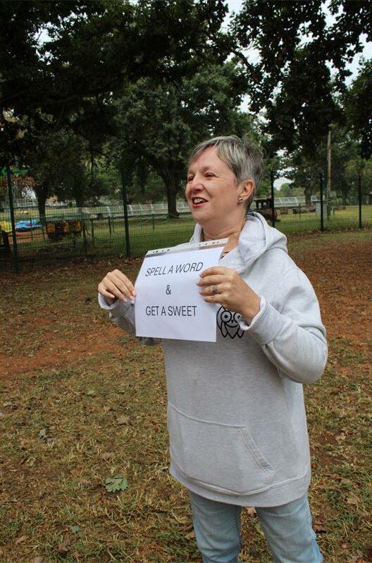 White woman with short grey hair holding a sign