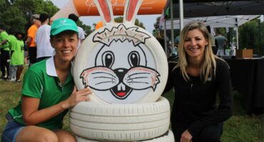 Two woman posing at a bunny display made from tyres.