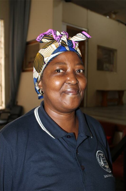 Black woman wearing a blue shirt and scarf covering her hair