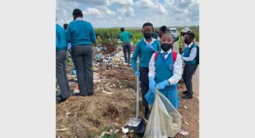 children picking up garbage,wearing school uniform.