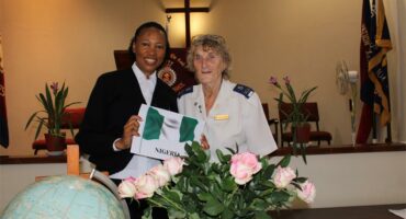 Black and white women standing behind pink roses and a globe
