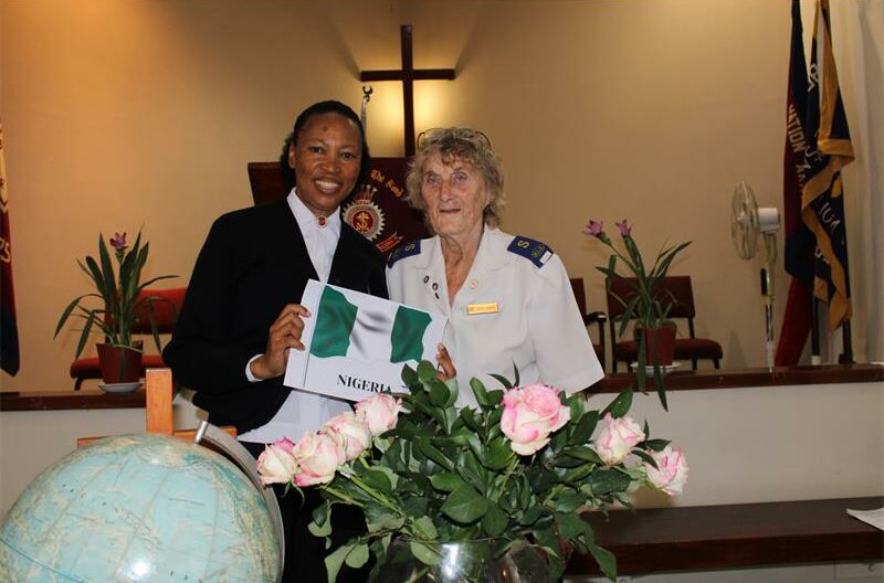 Black and white women standing behind pink roses and a globe