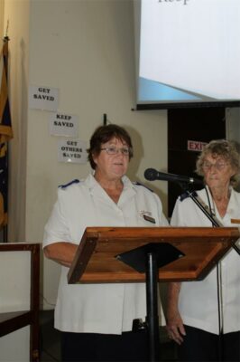 White woman with glasses standing behind a podium and speaking into a microphone