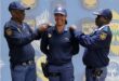 Two male police officers flanking a female officer