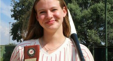 Girl stands with a baseball bat over her shoulder and holding a trophy