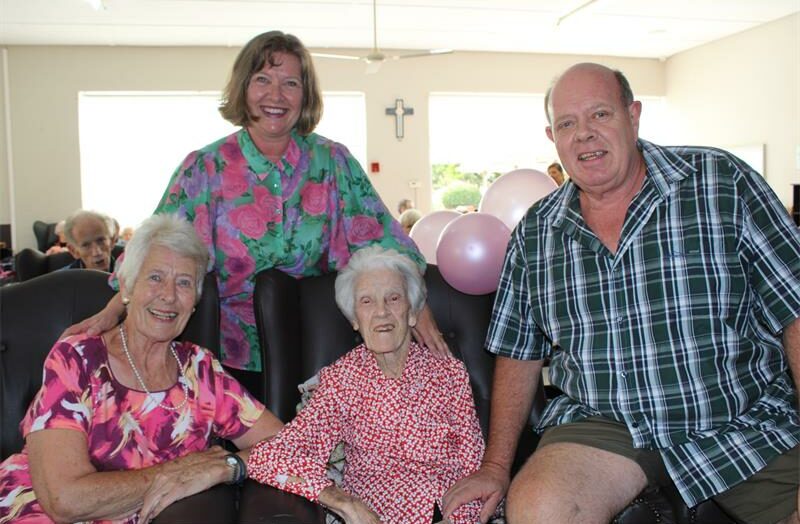 Vier mens sit geseelig en glimlag vir 'n foto