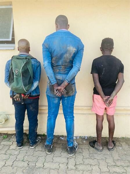 Three black men facing a wall