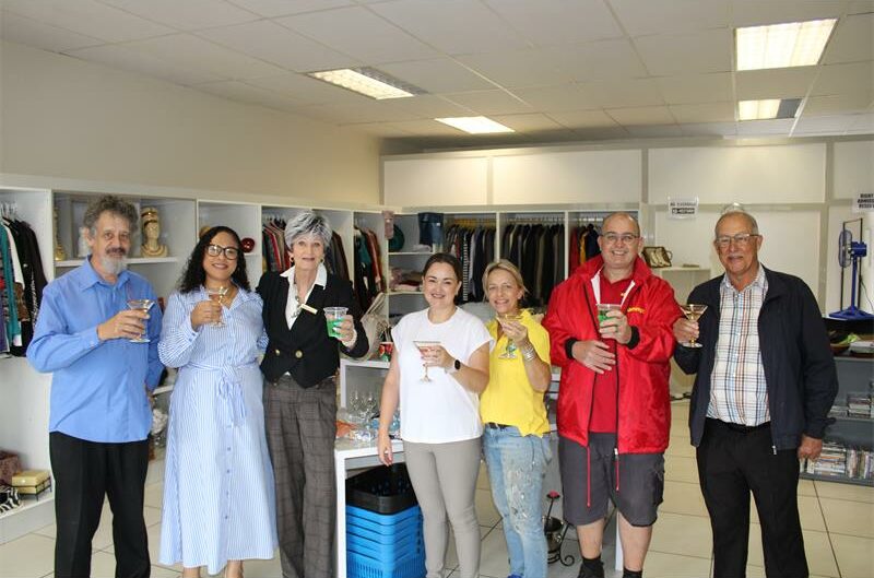 A group of men and women standing inside a shop holding glasses