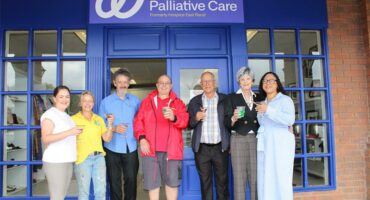 Group of men and women standing in front of a blue store front
