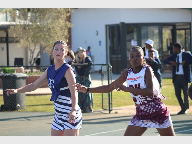 A netball player reaches out for the ball while her partner keeps an eye on the ball.