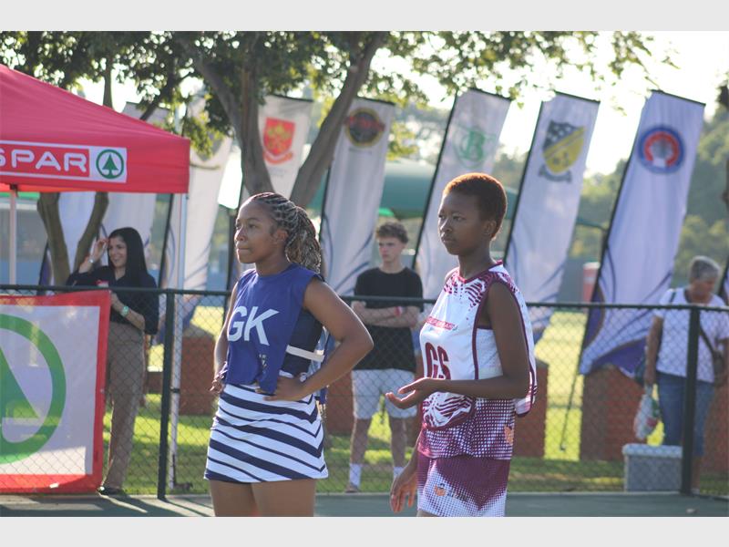Two netball players on a court standing next to each other looking at the game.